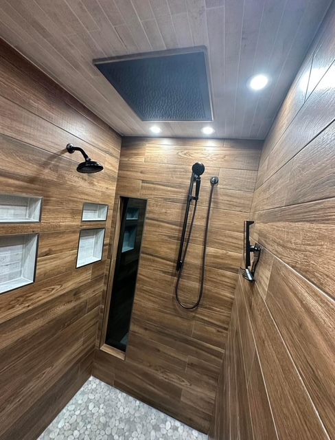 Custom walk-in shower with wood-look tile and pebble floor in a bathroom remodel